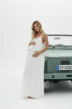 Pregnant model looking at camera in white dress with car - portrait