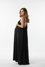 Pregnant model showing backless black dress in studio - portrait